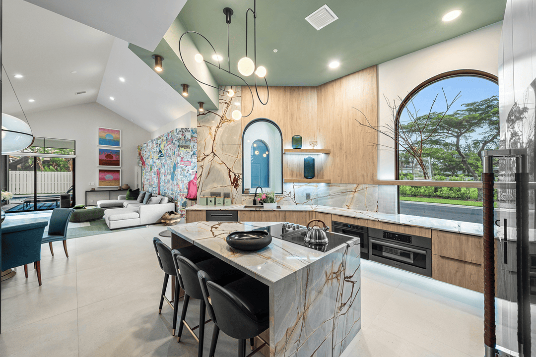 Open kitchen in a Broken Sound Boca Raton residence with a marble island and light wood cabinetry.